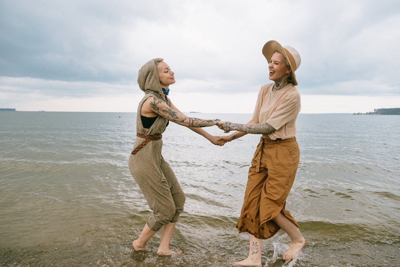 Friends enjoying a carefree day dancing on the beach, embracing laughter and happiness.