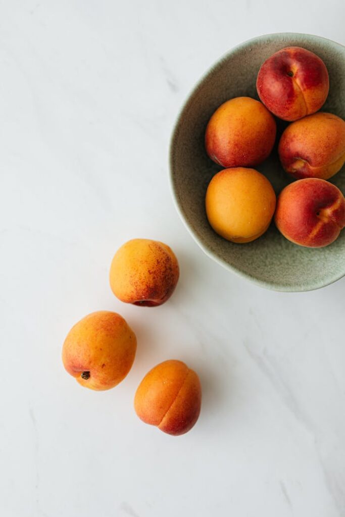pexels photo 4397786 Top view composition of delicious colorful peaches in green ceramic bowl and on white marble table