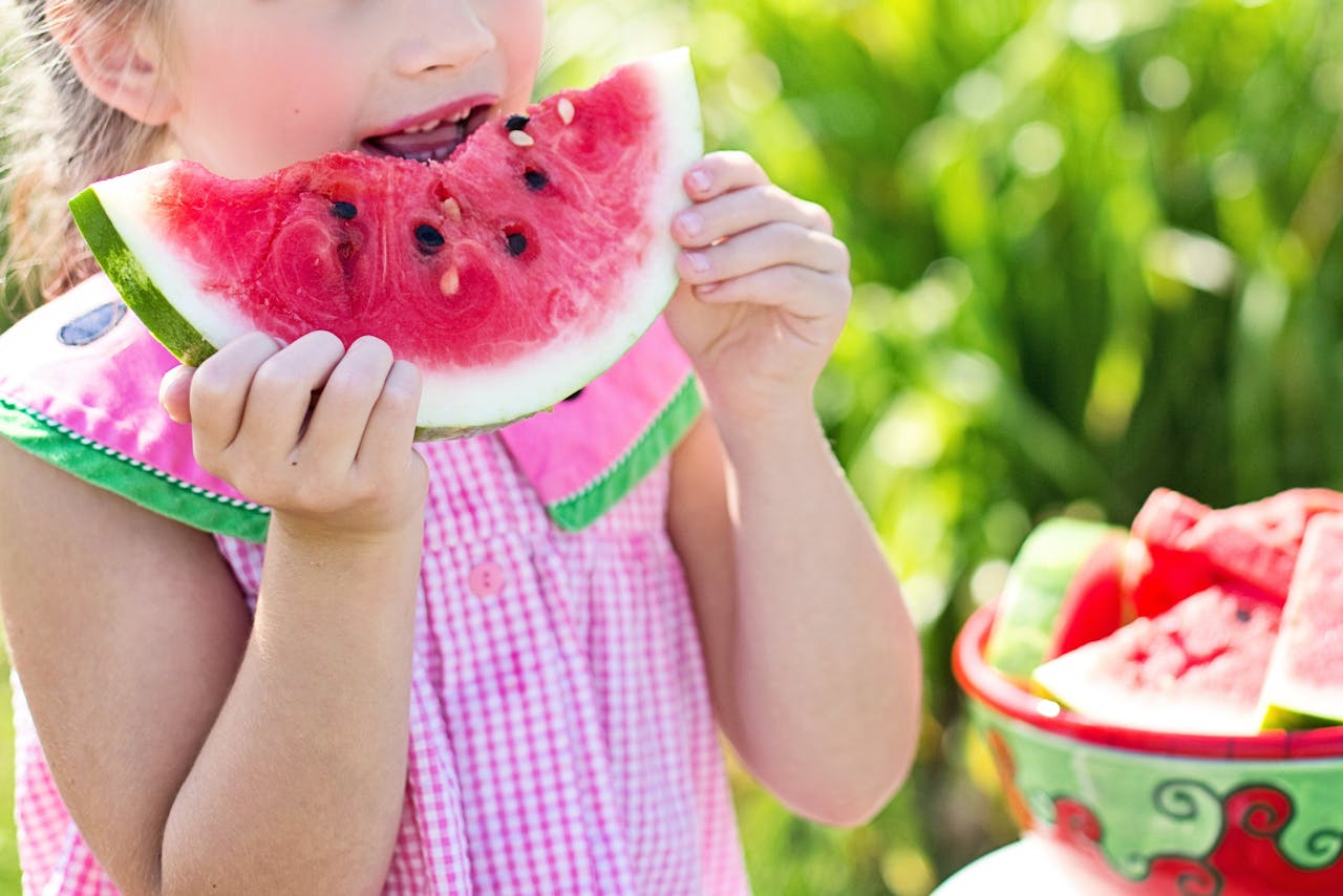 why-choose-us Young girl eating a juicy watermelon slice in a sunny outdoor setting, symbolizing summer refreshment.